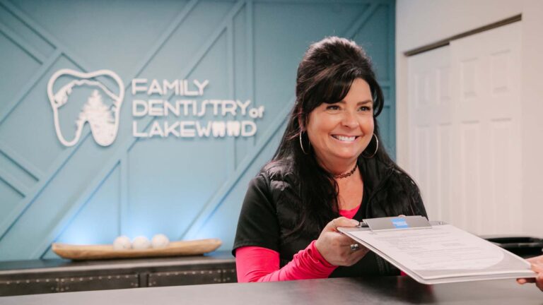 an employee at a dental office passes new patient paperwork